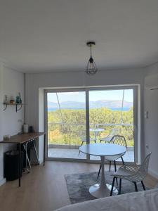 a living room with a table and chairs and a large window at Yialos Kalamos in Kalamos