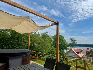 a canopy on a deck with a view of the water at Domek nad Drawskim in Stare Drawsko
