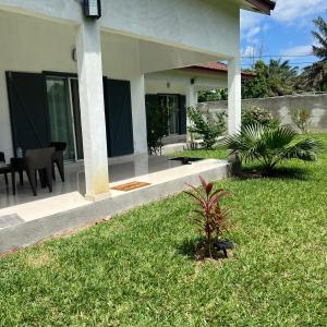 a house with a grassy yard with a table and chairs at La Villa Fleur d'Edene in Abidjan