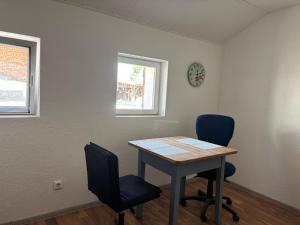 a room with a table and two chairs and a clock at Neubeginn 2 - Zimmer A in Hildburghausen