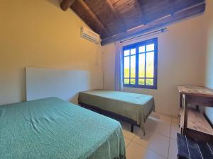 a room with two beds and a window at Residencial Hibiscos - Vista Mar in Garopaba