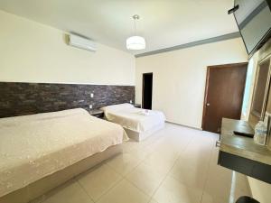 a bedroom with two beds and a tv in it at Hotel Morelos Colima in Colima