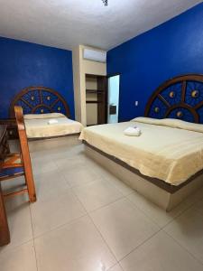 a bedroom with two beds and a blue wall at Hotel Morelos Colima in Colima