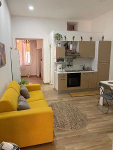 a living room with a yellow couch and a kitchen at Carpenters Guest House in Pompei