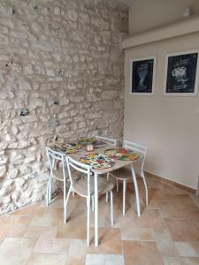 a table and chairs in a room with a stone wall at Maison de campagne proche Giverny La Casita de Bemi in Bois-Jérôme-Saint-Ouen