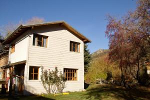 a white house with windows on the side of it at Los Coihues camping & hostel in San Carlos de Bariloche