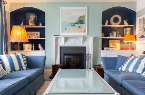 a living room with blue couches and a fireplace at Chy En Glas - By Rowes Retreats in Falmouth