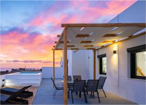 a patio with a table and chairs and a sunset at Aerial Villas in Imerovigli