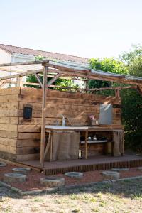 a wooden pergola with a table in a yard at Le Bunker Secret - Logement Insolite in Florensac