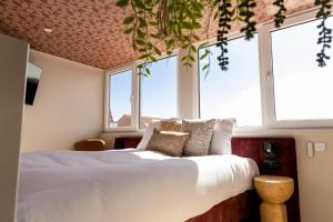 a bedroom with a bed with white sheets and windows at Boutique Hotel Charley's in Westkapelle +114 photos