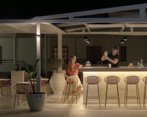 a woman sitting on a stool in front of a bar at Amalia Apartments-Suites in Bali