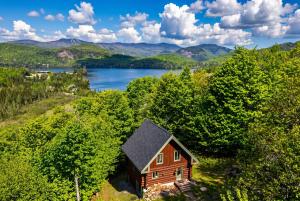 a house on a hill with a lake and mountains at Le Bois Dormant - Spa, Fireplace, Pool, Lake, Tennis in Lac-Superieur