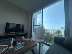 a living room with a television and a chair and a large window at Kıbrıs Town House Menekşe in Aglantzia