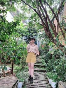 a woman standing in a garden talking on a cell phone at Pine Aura Dalat Inn in Da Lat +43 photos