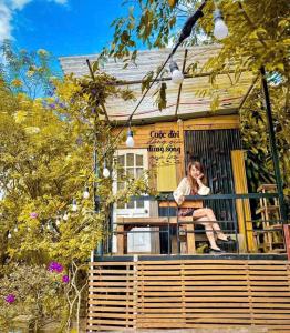 a woman sitting on the porch of a tiny house at Pine Aura Dalat Inn in Da Lat