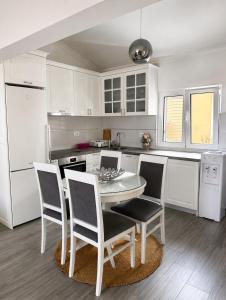 a white kitchen with a dining table and chairs at La Hacienda Percobic-Serenity & private pool in Bar