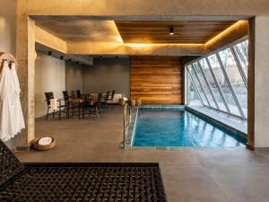an indoor pool with a dining room and a table at Refúgio Boutique com Piscina Aquecida in Canela