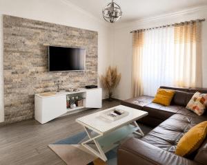 a living room with a couch and a tv on a brick wall at La Hacienda Percobic-Serenity & private pool in Bar