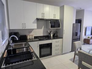 a kitchen with white cabinets and a sink at Galani Homes Comfort 2-Bed Suite in Gaborone +25 photos