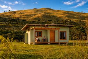 two people sitting on the porch of a small house at Vale Mandaçaia in Urubici