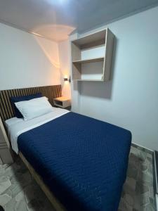 a bedroom with a bed with a blue blanket and a cabinet at ZIG ZAG Hospedaje in Tocancipá