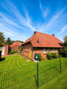 a brick house with a fence in the yard at Ferienhaus Schonerweg 9 in Norddeich in Norddeich