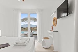 a white room with a bed and a television at Ariadne's Crown Luxury AstroConcept Suites with Private Pools and Spas in Vívlos