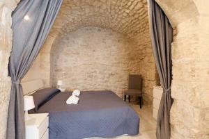 a white teddy bear sitting on a bed in a bedroom at Casa Nerina in centro Scicli in Scicli