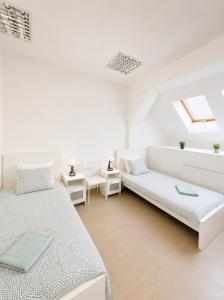 a white room with two beds and a couch at Konvoj szálló in Budapest
