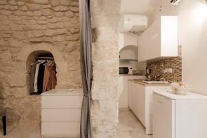 a kitchen with white cabinets and a stone wall at Casa Nerina in centro Scicli in Scicli +24 photos