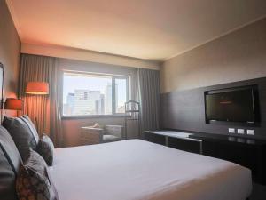 a hotel room with a bed and a flat screen tv at Mercure Santiago Centro in Santiago