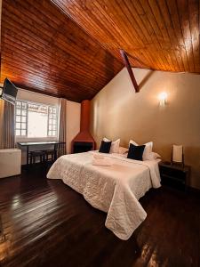 a bedroom with a large bed with a wooden ceiling at Pousada Alto do Vale in Nova Friburgo