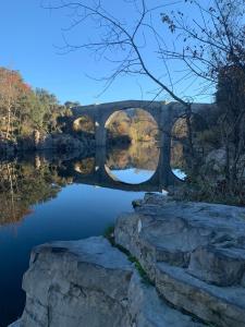 a stone bridge over a river with a reflection in the water at Entre Pic et Rivière in Saint-Martin-de-Londres