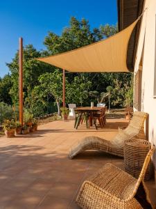 a patio with a table and chairs and a large umbrella at Terrazza Ganzaria in San Michele di Ganzaria