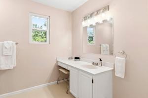 a white bathroom with a sink and a mirror at Spacious Edgewater Home Deck & Sleeps 10 in Edgewater