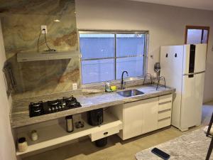 a kitchen with a sink and a white refrigerator at Casa na praia prática aconchegante in Serra