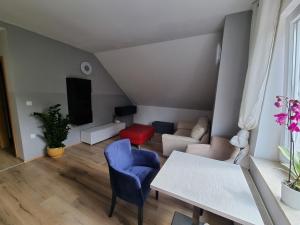 a living room with a white table and blue chairs at Apartma 8 in Pekre