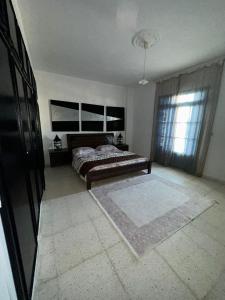 a bedroom with a bed and a large window at Appartement henda 01 in Sousse