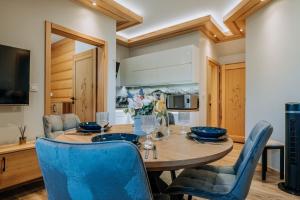 a dining room with a wooden table and blue chairs at Apartament Między Górami in Kacwin