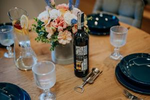 a bottle of wine sitting on a table with glasses at Apartament Między Górami in Kacwin