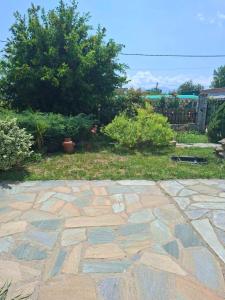 a stone patio in a yard with bushes and trees at IVY Traditional House in Amigdhaleón