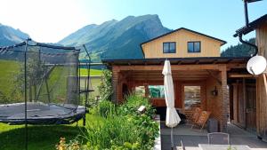 a house in the mountains with a patio and an umbrella at Appartment Waldtraum in Au im Bregenzerwald