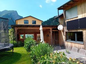 a house with a patio and an umbrella in the yard at Appartment Waldtraum in Au im Bregenzerwald