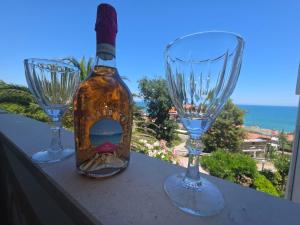 due bicchieri da vino e una bottiglia appoggiati su una mensola di Pubble beach apartment a Fossacesia Altre 15 foto