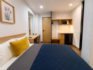a hotel room with a bed with a yellow pillow at Aloja Rentals Mexico in Mexico City