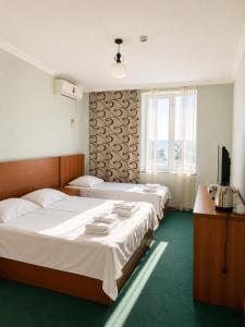 a hotel room with two beds and a television at Renesans Hotel Kobuleti in Kobuleti