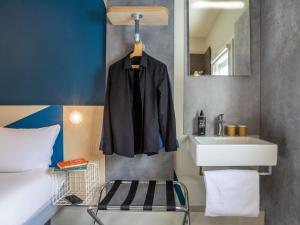 a black jacket hanging on a wall next to a sink at ibis budget Haguenau Strasbourg Nord in Haguenau +85 photos