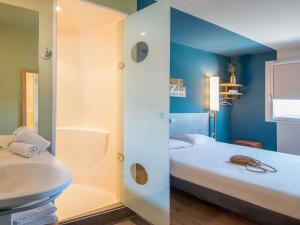 a bathroom with a bed and a shower and a sink at ibis budget Pertuis Portes du Luberon in Pertuis