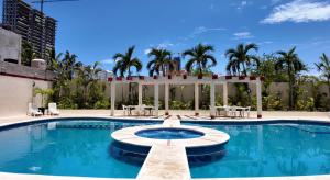a pool at a hotel with palm trees at Hotel RRU Diamante in Acapulco