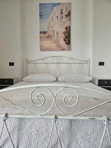 a white bed in a bedroom with a painting on the wall at B&B Helios in Nardò +29 photos